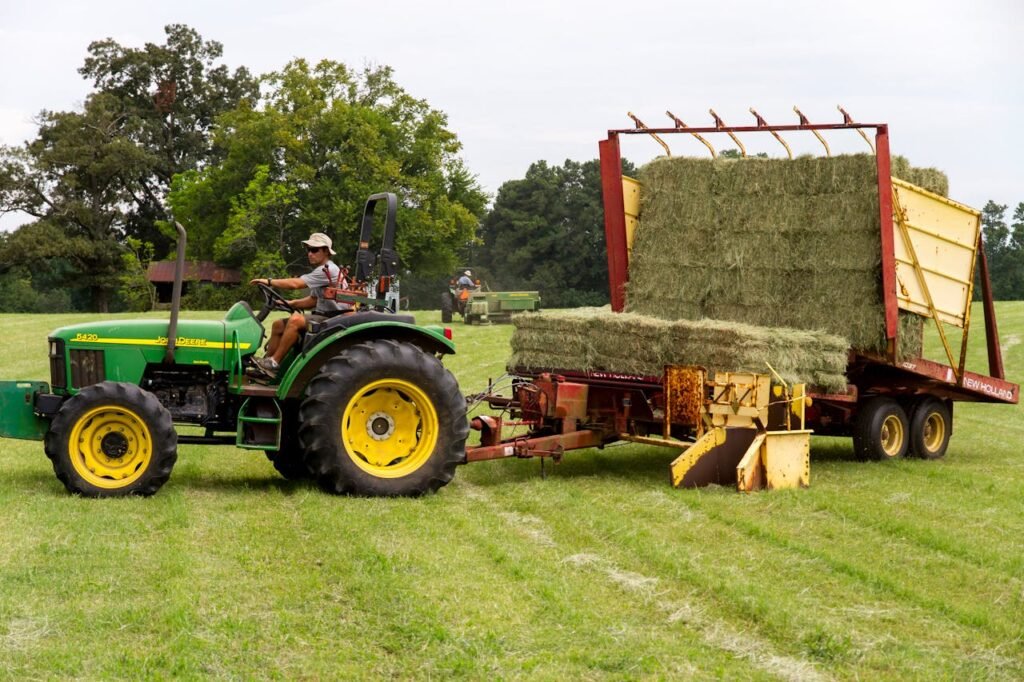 Man Riding On Riding Mower Carrying Hays In The Middle Of Field